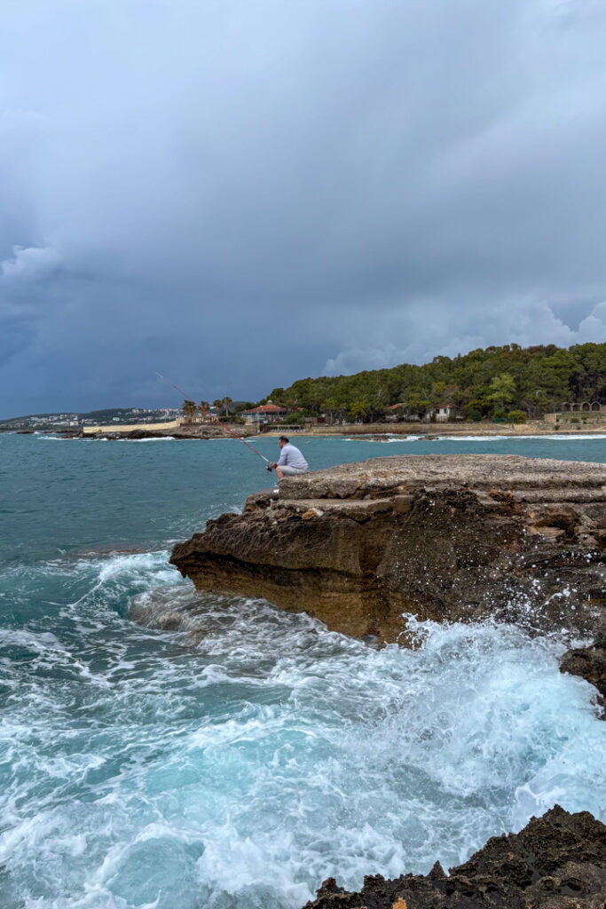 Ein Angler auf einem Fels am Meer