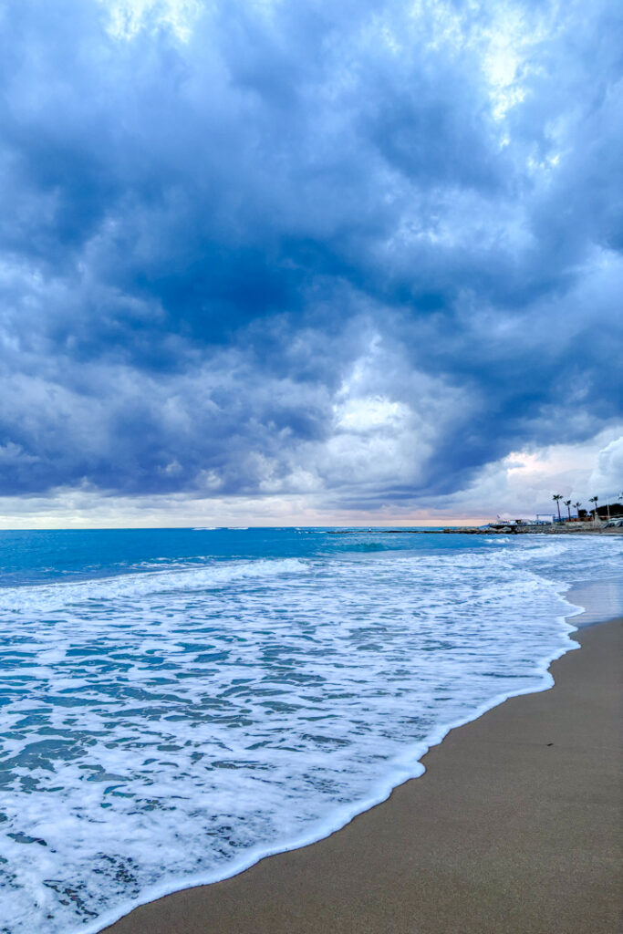 Strand mit blauem Meer und einer dunklen Wolkendecke