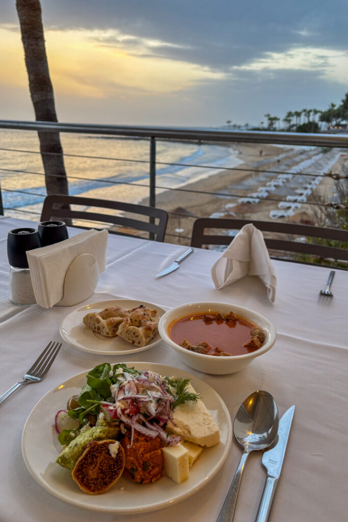 Ein Tisch mit Tellern voller Essen und Ausblick auf das Meer