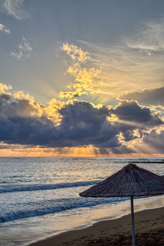 Sonnenuntergang am Meer mit einem Sonnenschirm im Vordergrund