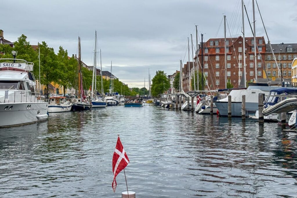 Eine dänische Flagge im Vordergrund und Blick auf einen Kanal mit Booten