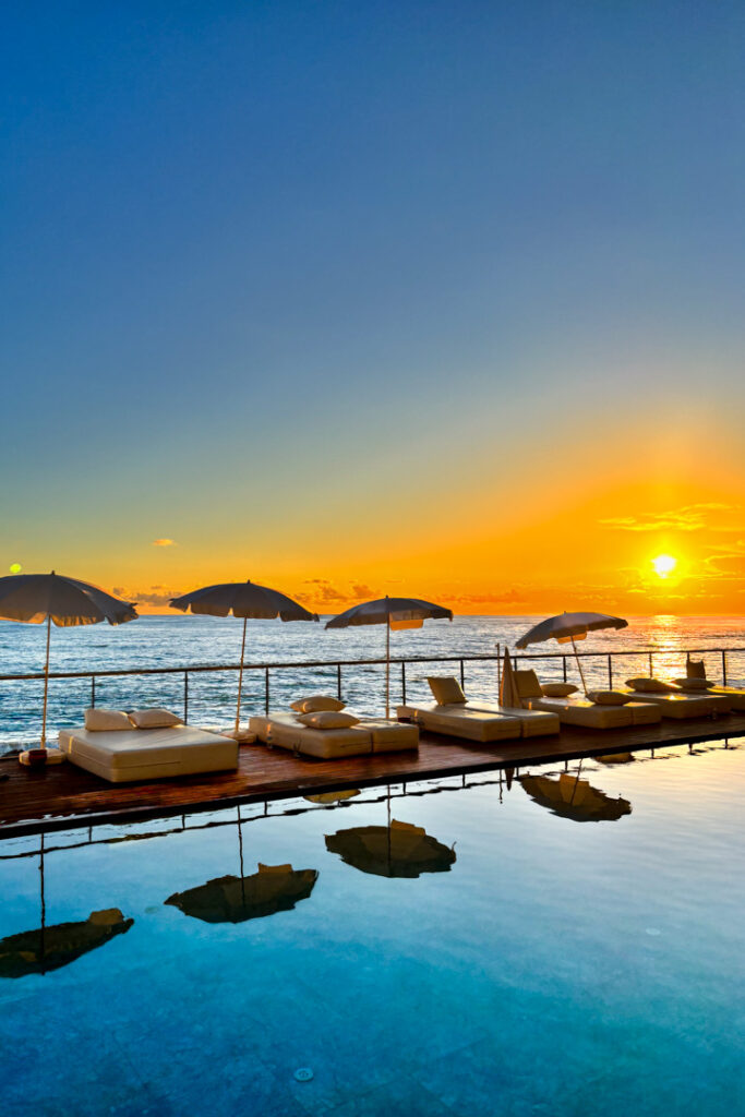 Pool mit Sitzkissen und im Hintergrund ein Sonnenuntergang