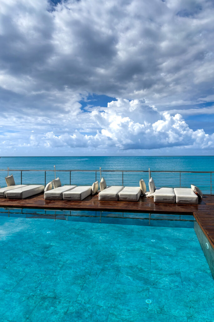 Ein Pool mit Kissen und im Hintergrund das Meer