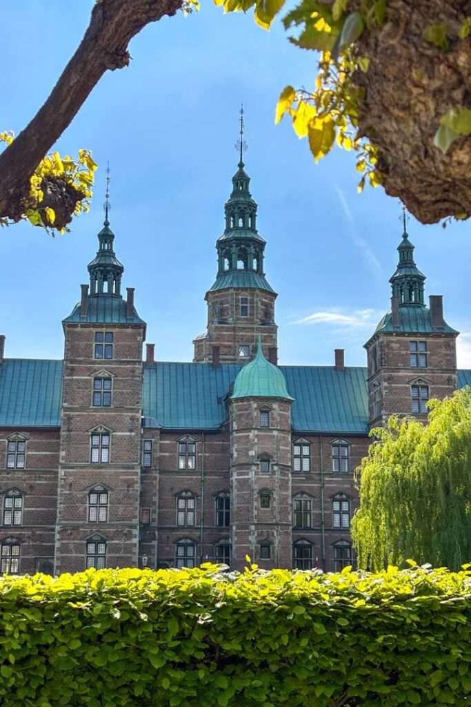 Ein Schloss mit Türmen hinter einer grünen Hecke