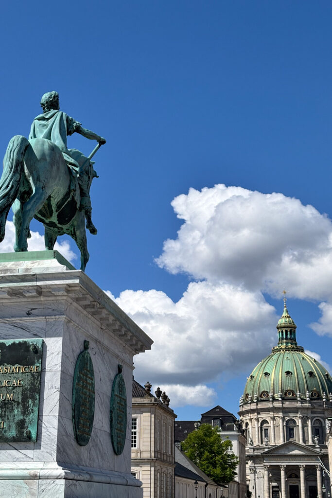 Ein Standbild mit Reiter, eine Kirche mit großer Kuppel und Wolken am Himmel
