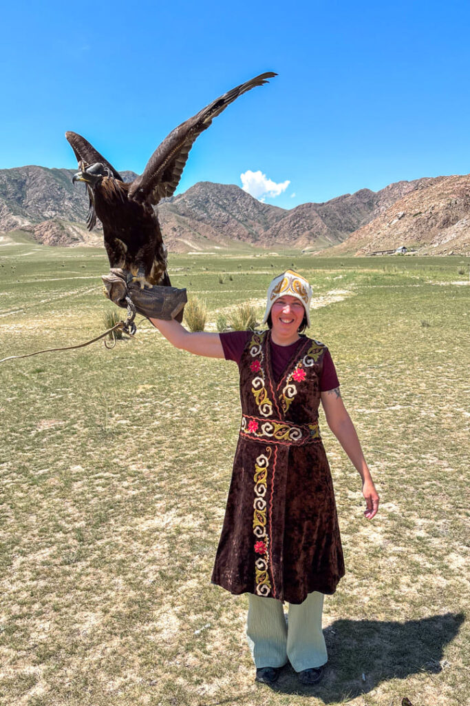 Eine Frau in einem traditionellen Gewand, die einen Adler hält