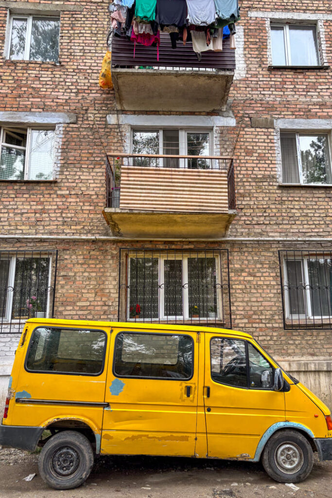 Gelber Kastenwagen vor einer alten Häuserwand