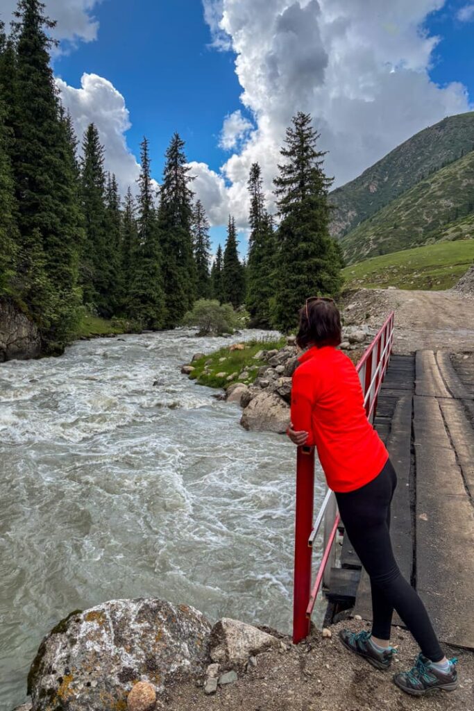 Eine Frau steht an einem Gelände und schaut auf einen reißenden Fluss