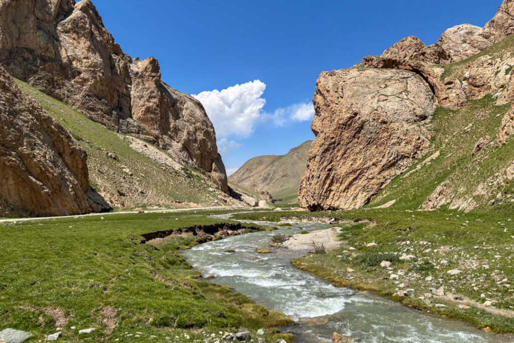 Ein ruhiger Fluss inmitten von hohen Felswänden und grünen Wiesen