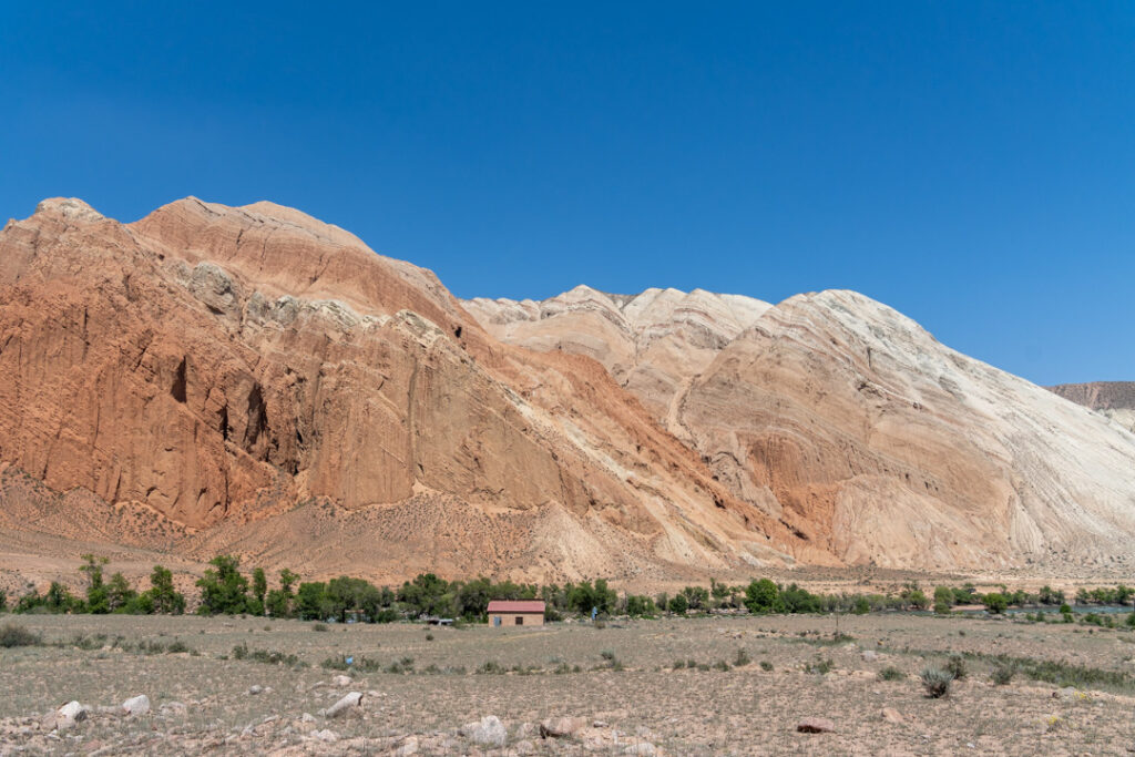 Ein roter Felsen unter blauem Himmel und einem Haus