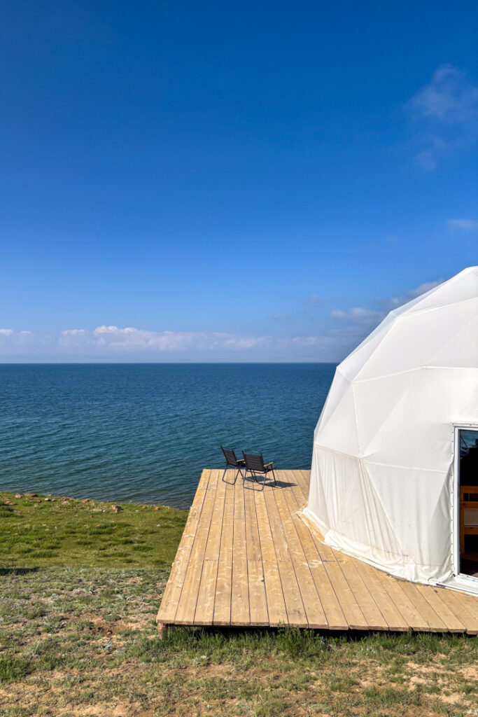 Eine Holzterrasse mit einem Zelt vor einem blauen See