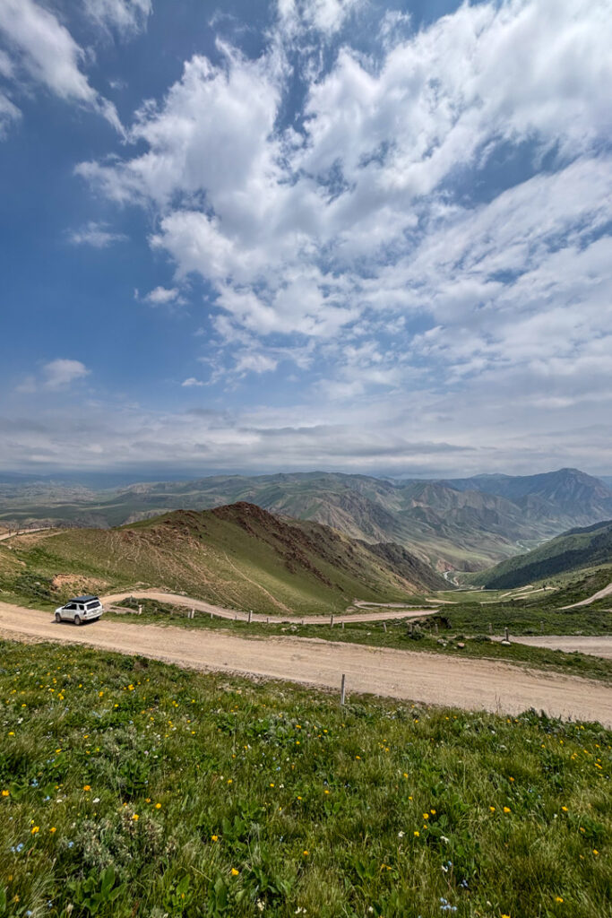 Ein Auto steht vor einem Bergpass mit Serpentinen