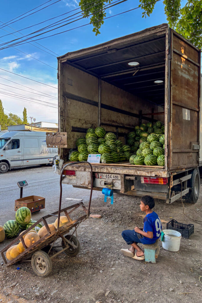 Ein Junge sitzt vor einem LKW voller Wassermelonen