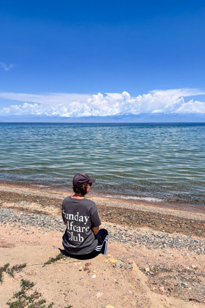 Eine Frau sitzt an einem blauen See 