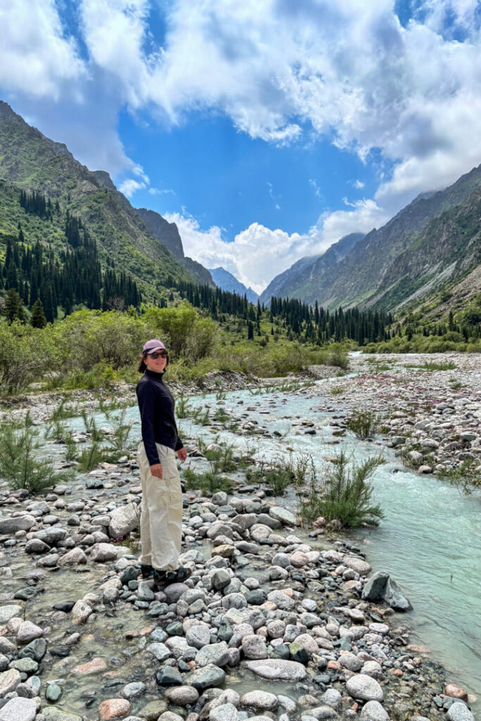 Eine Frau steht in einer Landschaft mit Fluss und Bergen
