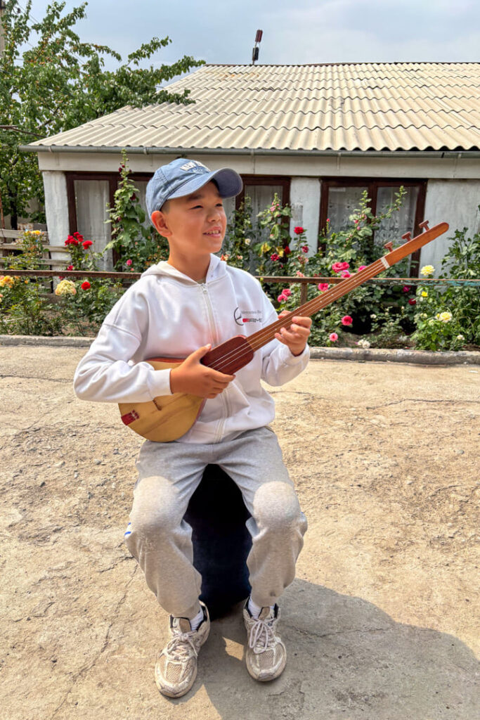 Ein Junge sitzt auf einem Hocker, während er ein Instrument spielt