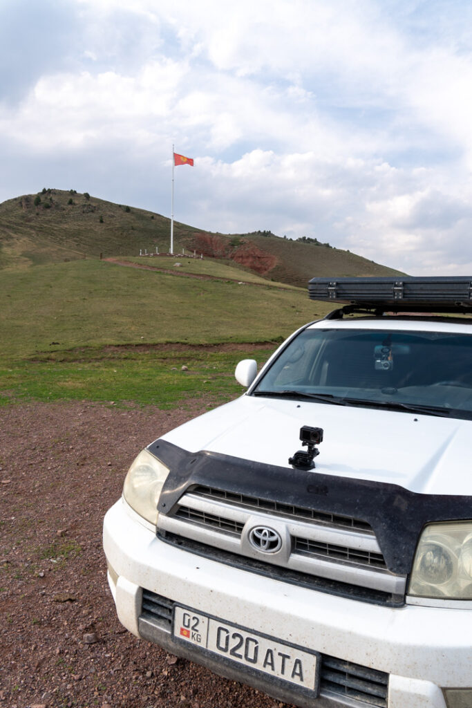 Ein Auto von vorn steht auf einem Hügel und mit Flagge im Hintergrund