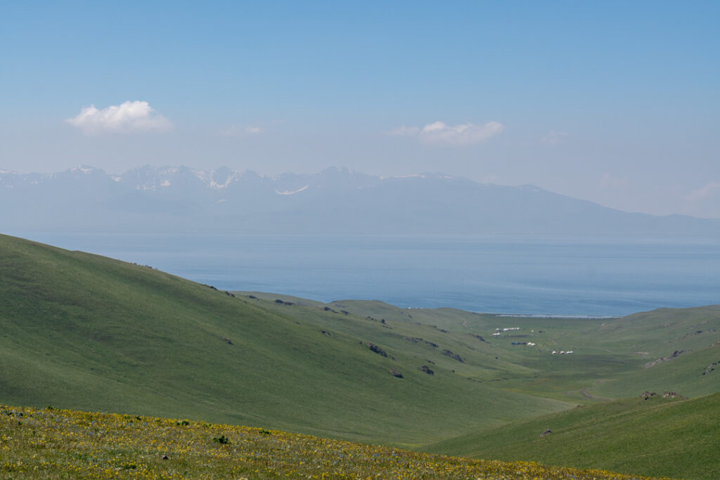 Eine weite grüne Landschaft mit See un Bergen