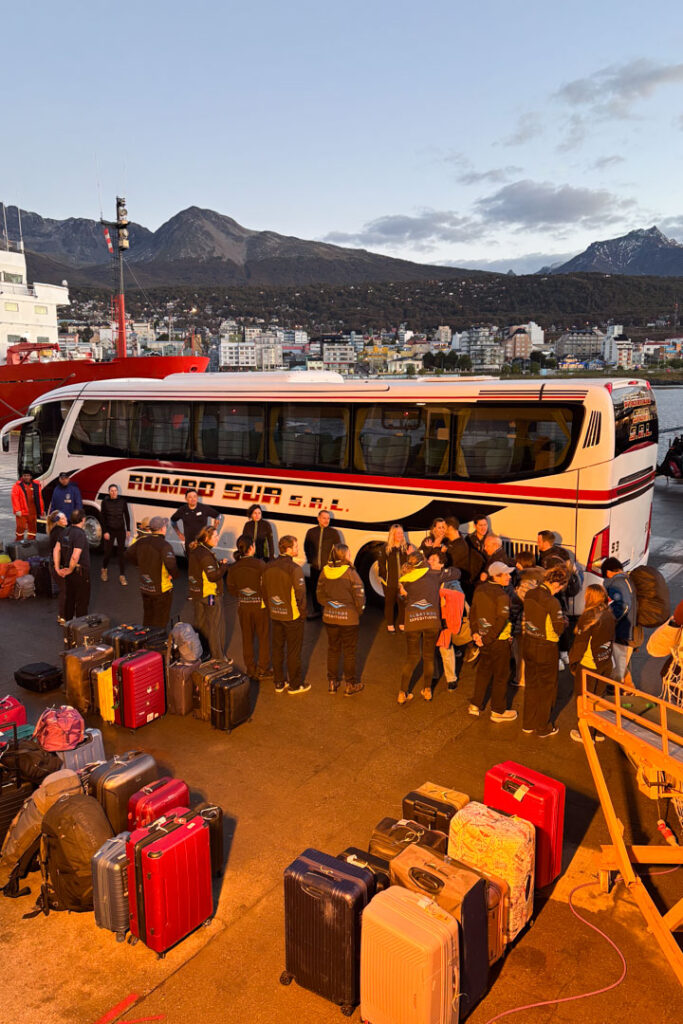 Eine Gruppe von Menschen steht in der Morgendämmerung von Ushuaia an einem Reisebus
