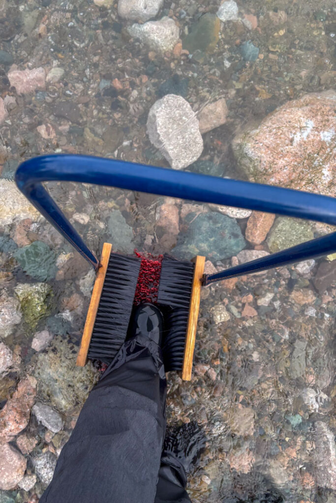 Ein Stiefel wird mit einer Bürste im Wasser sauber gemacht