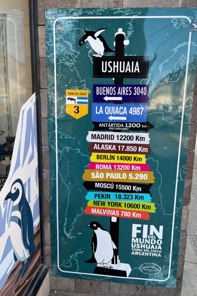 Ein Schild mit Orten und Pfeilen in Ushuaia
