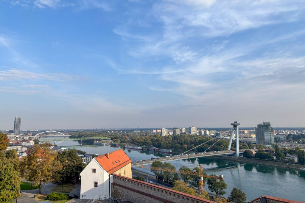 Weite Aussicht von der Burg Bratislava auf die Donau, die moderne Brücke „Most SNP“ mit ihrem markanten UFO-Turm und die Stadtlandschaft