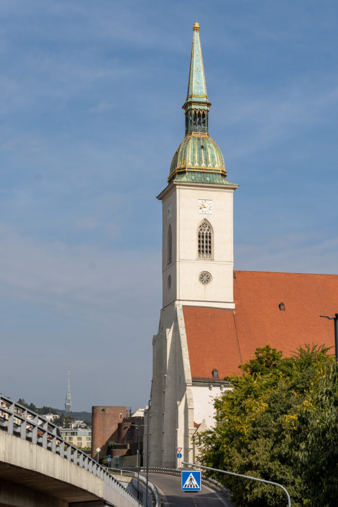 Der markante, weiße Turm des Martinsdoms mit seiner grün-goldenen Kuppel vor blauem Himmel in Bratislava