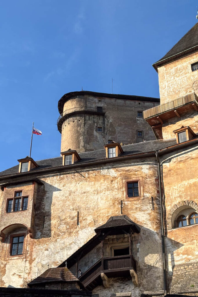 Nahaufnahme der imposanten, auf einem Felsen thronenden Arwaburg (Oravský hrad) unter blauem Himmel