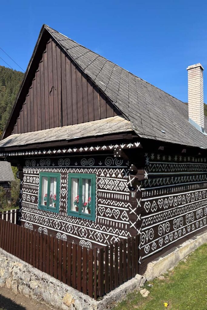 Ein traditionelles dunkles Holzhaus im slowakischen Dorf Čičmany, verziert mit den typischen weißen, geometrischen Volkskunstmustern
