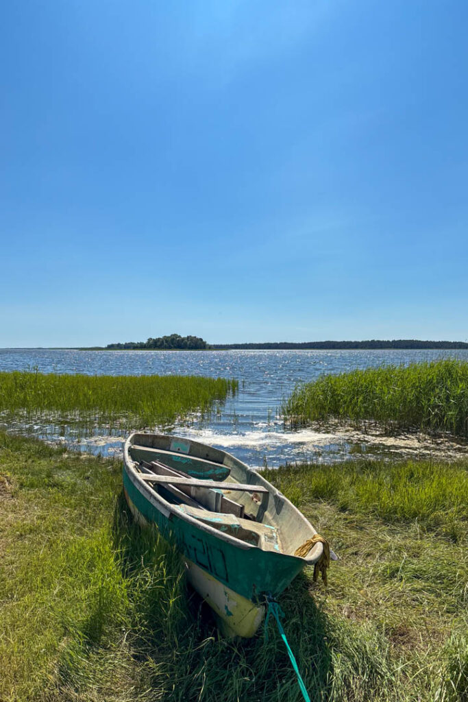 Ein Holzboot liegt am Ufer eines glitzernden Sees