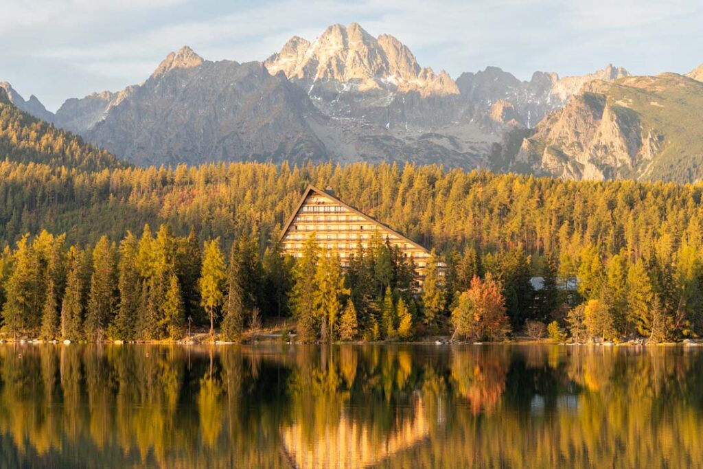 Am Ufer des Bergsees Štrbské Pleso in der Hohen Tatra, im Hintergrund spiegelt sich das markante Hotelgebäude vor den Bergen